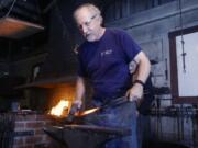 Master blacksmith Jay Close uses a hammer and anvil to flatten metal that will be curved to hold the handle of a garden rake.