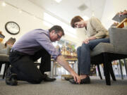 When the Shoe Fits owner Alan O'Hara helps customer Christy Quinn try on shoes at the company's Fisher's Landing store.