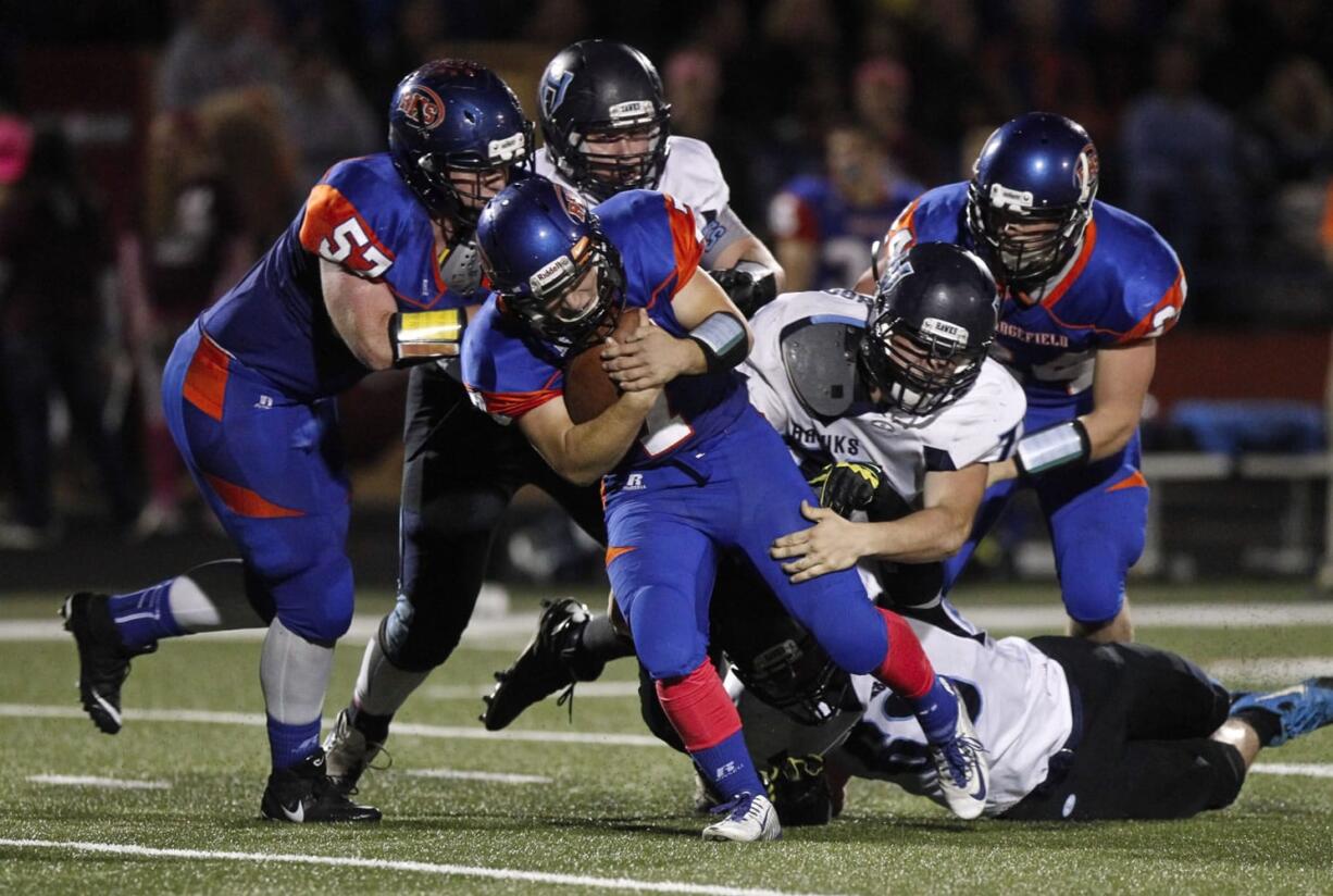 Hockinson defenders including Taylor Lindsley and Ryan Sleasman bring down Ridgefield quarterback Jarrett Mocca (7) during Friday’s Class 2A Greater St. Helens League showdown Friday in Ridgefield. Hockinson won, 17-7, to remain undefeated and hand Ridgefield its first loss of the season.