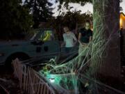 Grace Sherman, left, and her twin sister, Lucy Sherman, both 14, help apply spiderwebs to the exterior of their neighbors&#039; house Tuesday evening in northwest Vancouver.