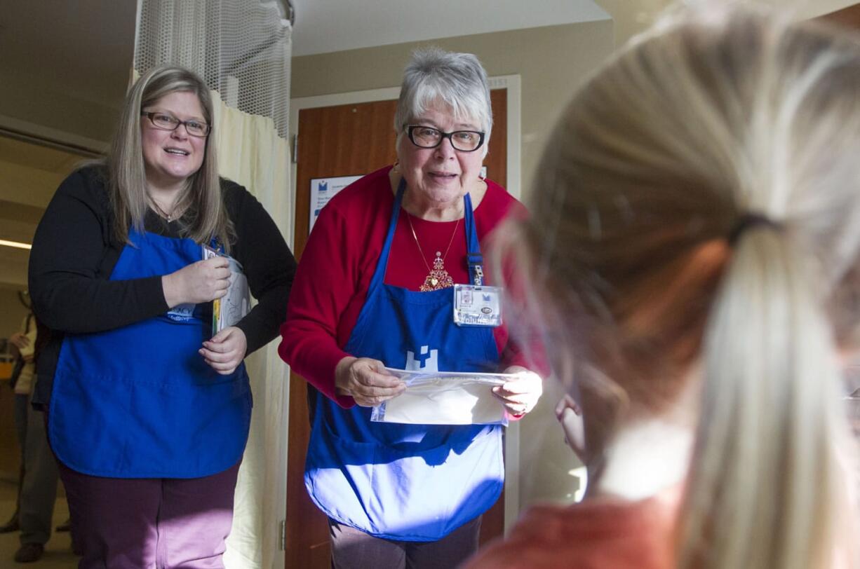 Jeanne Al-Ghamdi, left, and her mother, Diana Webber, greet children as they make the rounds with Sam's Art Cart at Legacy Salmon Creek Medical Center on Dec. 19.