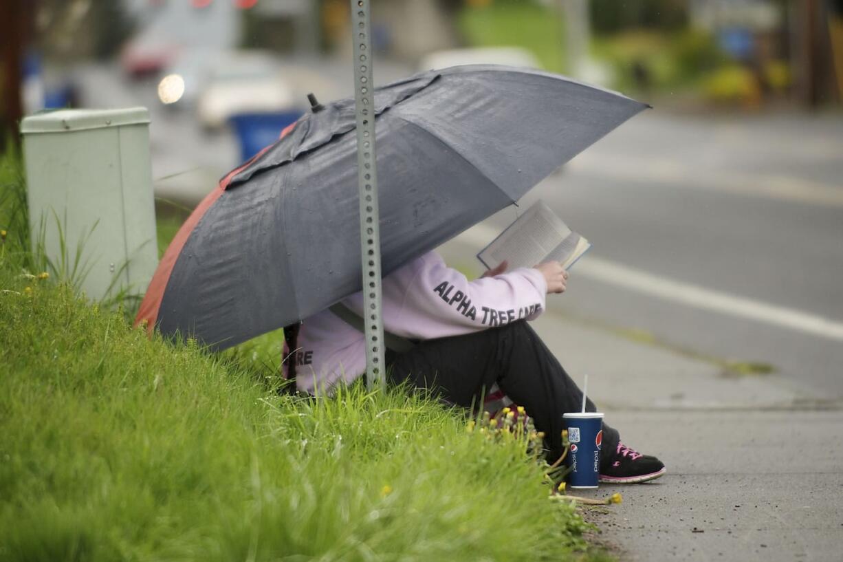 Anna Hancock of Vancouver reads a book while waiting for the No. 9 bus on her way home from work Tuesday.