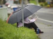 Anna Hancock of Vancouver reads a book while waiting for the No. 9 bus on her way home from work Tuesday.