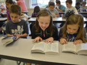 Washougal: Gause Elementary School third-graders Cameron Miller, from left, Chloe Baker and Peyton Del Carlo flip through the dictionaries they received from the Camas-Washougal Rotary.