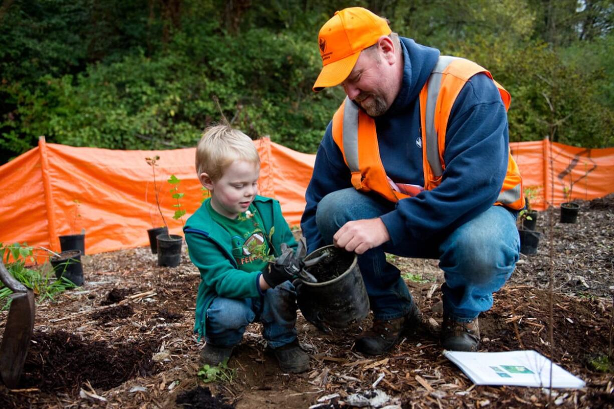 Vancouver city employee Tony Collins helps Lukas Young, 4, remove a sapling from its pot during a tree-planting in Vancouver on Saturday. The event, coordinated by the Vancouver Watersheds Alliance, was among several in the area that coincided with national Make a Difference Day. (Molly J.