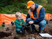 Vancouver city employee Tony Collins helps Lukas Young, 4, remove a sapling from its pot during a tree-planting in Vancouver on Saturday. The event, coordinated by the Vancouver Watersheds Alliance, was among several in the area that coincided with national Make a Difference Day. (Molly J.