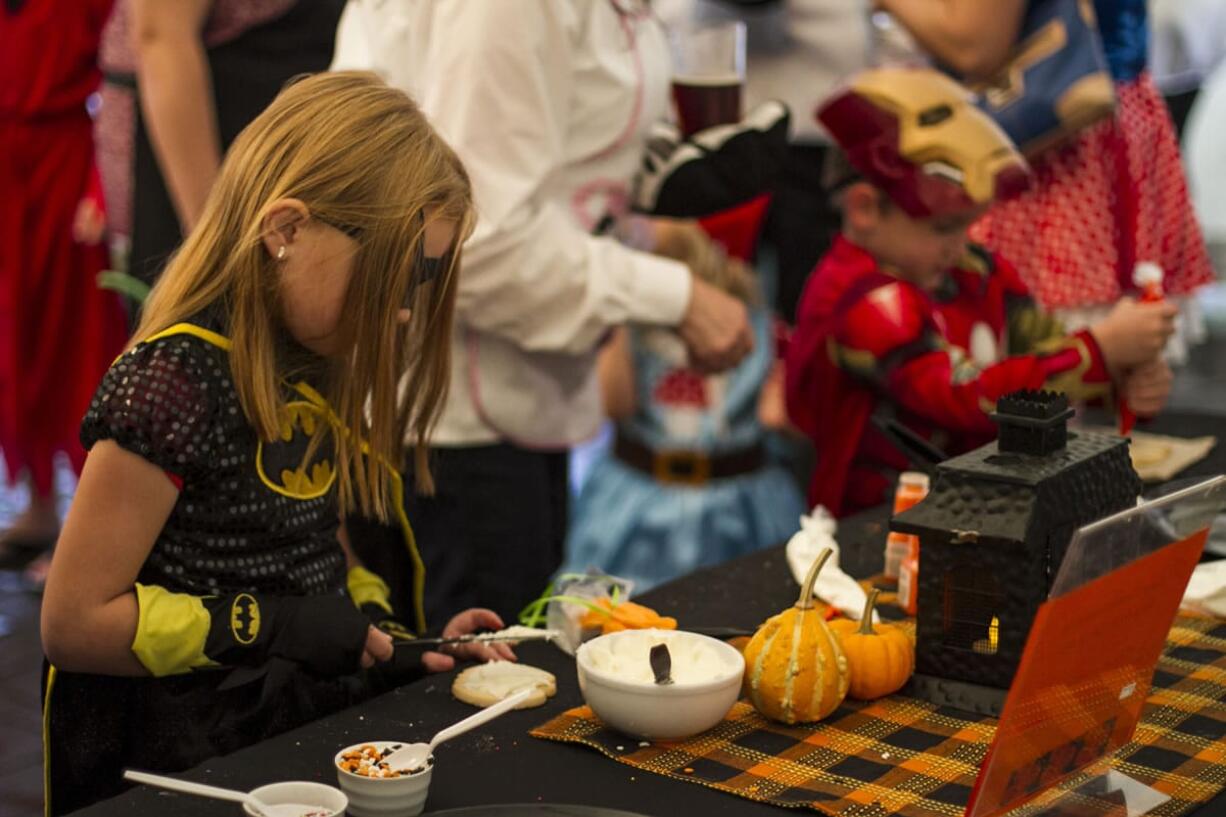 Lily Harmier, dressed as a fierce Batgirl, decorated a pumpkin cookie at Latte Da's Halloween costume party in Vancouver on Saturday.