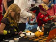 Lily Harmier, dressed as a fierce Batgirl, decorated a pumpkin cookie at Latte Da's Halloween costume party in Vancouver on Saturday.