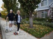 Gregg Teaby, left, and his daughter, Celeste Child, who had a stroke five years ago, test motorized canes on the sidewalk in front of Teaby&#039;s Camas home. Teaby, a retired medical device engineer, created two versions of the cane and is finishing up the third, which he is working to make lighter and more cost-effective than the others.