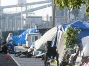 Residents sit at a homeless encampment in Vancouver earlier this month. Last weekend, a group of gun-toting volunteers patrolled the camp at night to provide security to the homeless living there. The group intends to return this weekend.