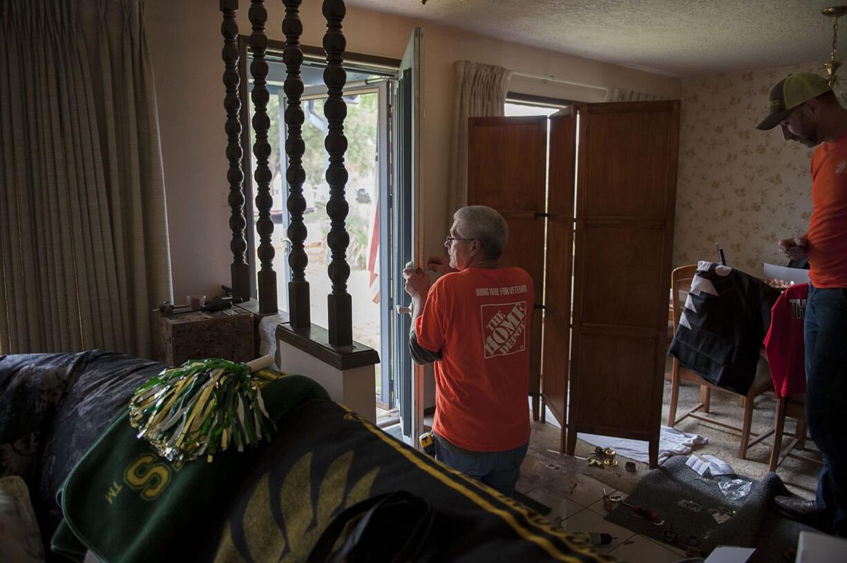 Home Depot volunteer Troy Vickery installs a new lock on the front door of Richard H.