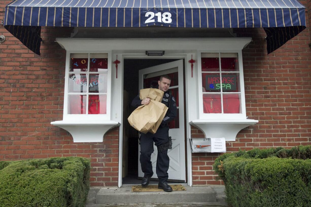 Police Cpl. Neil Martin removes evidence during a search Tuesday at Nancy's Studio, 218 W. 13th St.