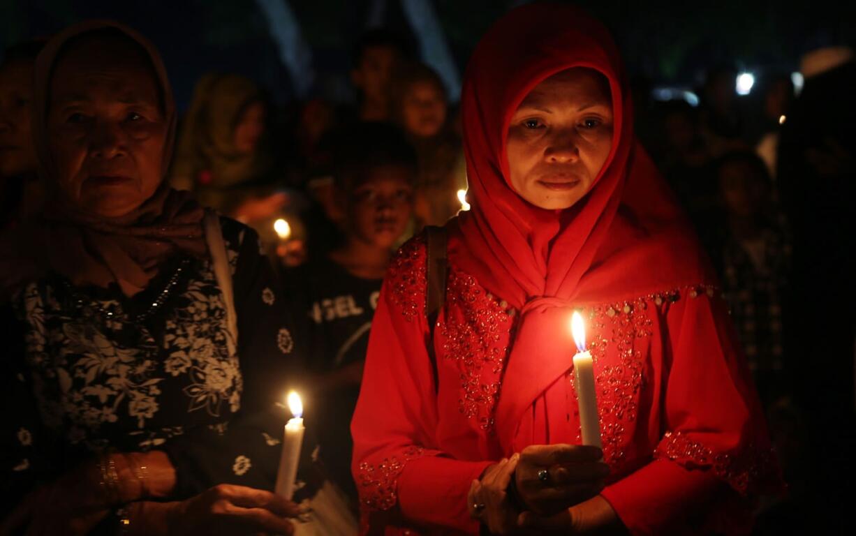 Indonesian women  hold candles to pray for the victims of AirAsia Flight 8501 in Pangkalan Bun, Indonesia, today.