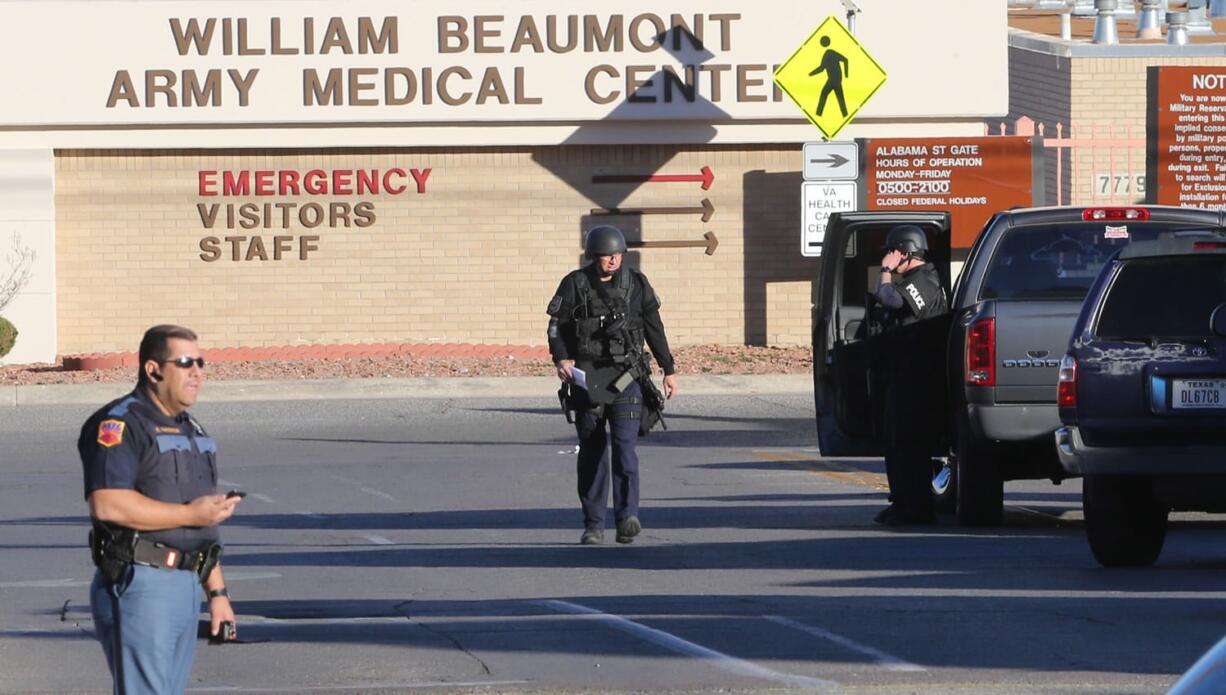 A armor-clad SWAT officer, center, heads to a staging area Tuesday outside the campus of the Beaumont Army Medical Center/El Paso Va. A gunman opened fire at the veterans' medical clinic in West Texas on Tuesday, killing one other person, officials said.