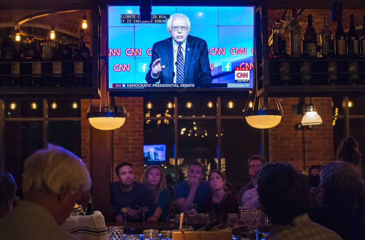 People watch the Democratic presidential debate from Las Vegas at a restaurant in Winooski, Vt., on Tuesday. The Vermont Democratic Party sponsored the debate-watching party. Sen. Bernie Sanders of Vermont is on the television screen.