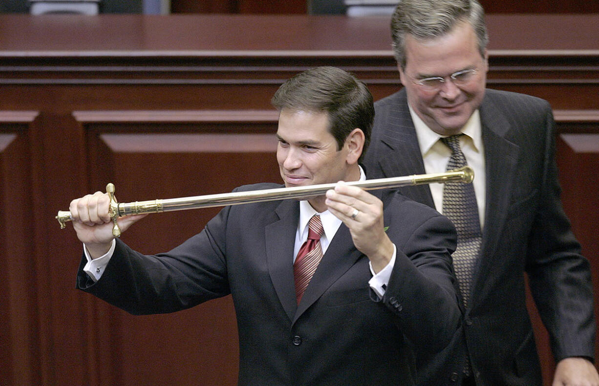 FILE - In this Sept. 13, 2005, file photo, then-Florida state Rep. Marco Rubio, left, holds a sword presented to him by then-Florida Gov. Jeb Bush during ceremonies designating Rubio as the next Florida Speaker of the House in Tallahassee, Fla. Bush and Marco Rubio are on course for a collision. There once was mutual public deference. But that has eroded as the Florida Republicans battling for the presidential nomination have come to see each other as the main threat to lofty ambitions: Bush's claim to the party establishment's mantle, Rubio's wish to become the new national face of the party.