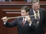 FILE - In this Sept. 13, 2005, file photo, then-Florida state Rep. Marco Rubio, left, holds a sword presented to him by then-Florida Gov. Jeb Bush during ceremonies designating Rubio as the next Florida Speaker of the House in Tallahassee, Fla. Bush and Marco Rubio are on course for a collision. There once was mutual public deference. But that has eroded as the Florida Republicans battling for the presidential nomination have come to see each other as the main threat to lofty ambitions: Bush's claim to the party establishment's mantle, Rubio's wish to become the new national face of the party.