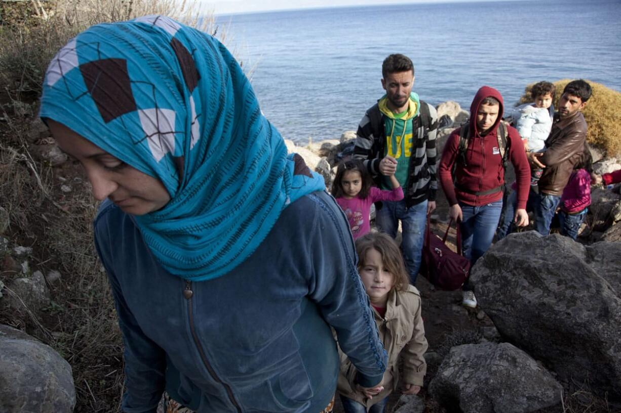 Syrian refugees walk on the rocks after arriving from Turkey onto the shores of the Greek island of Lesbos, in a inflatable dinghy Monday. Greece is the main entry point to the European Union for hundreds of thousands of people fleeing war and poverty in the Middle East and Africa.