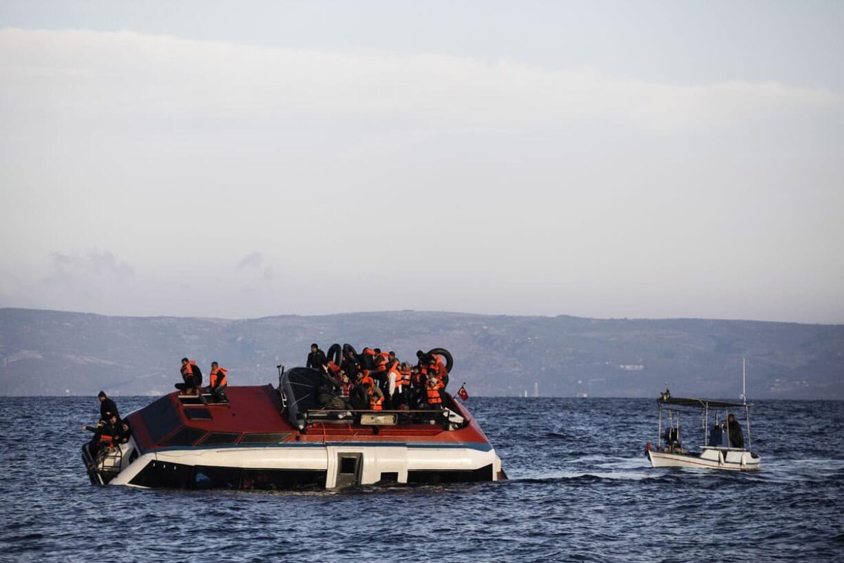 Refugees and migrants sit atop a heavily-listing small vessel as they try to travel from the Turkish coast to Skala Sykaminias on the northeastern Greek island of Lesbos on Friday, Oct. 30, 2015. Authorities in Greece say 21 people have died in other islands after two boats carrying migrants and refugees from Turkey to Greece sank overnight, in the latest deadly incidents in the eastern Aegean Sea.