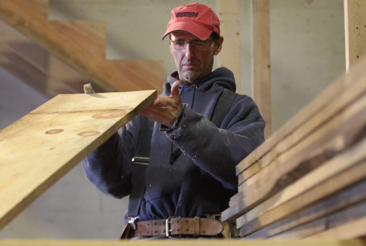 Ken Voorhees examines a board for defects while building a stairway for a customer in Lisbon, Maine. Voorhees, who is self-employed, signed up for health insurance with Maine Health Community Options.