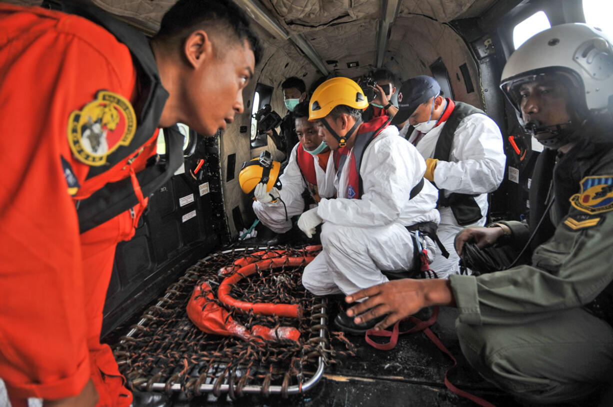 Indonesian rescuers confer on an Air Force NAS 332 Super Puma helicopter during the search operation for the victims and the wreckage of AirAsia Flight 8501 over the Java Sea off Pangkalan Bun, Central Borneo, Indonesia, on Tuesday.