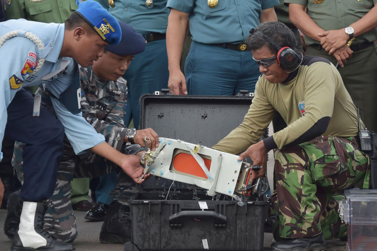 Indonesian military personnel remove Flight Data Recorder of the ill-fated AirAsia flight QZ8501 into a proper case in Pangkalan Bun, Indonesia, Monday, Jan. 12, 2015. Divers retrieved one black box Monday and located the other from the AirAsia plane that crashed more than two weeks ago, a key development that should help investigators unravel what caused the aircraft to plummet into the Java Sea.