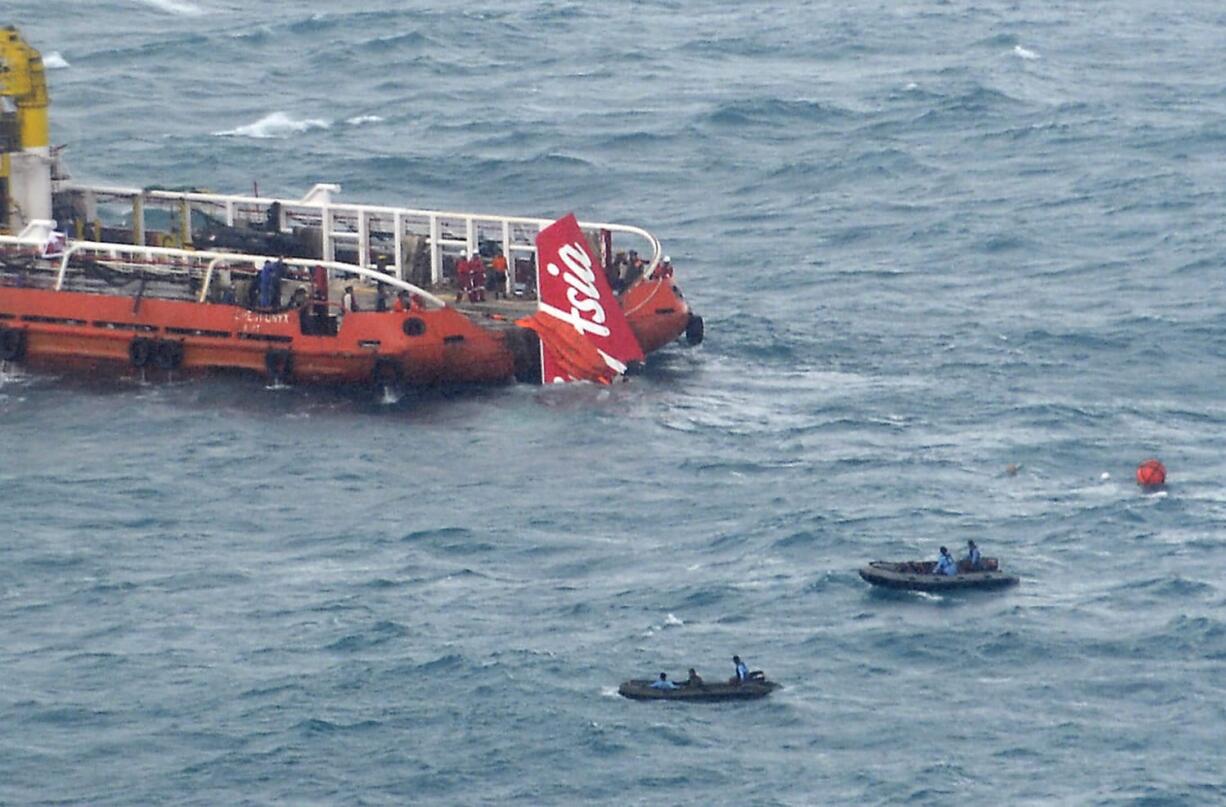 Rescuers lift portion of the tail of AirAsia Flight 8501 onto the deck of a rescue ship after it was recovered from the sea floor on the Java Sea, Saturday, Jan. 10, 2015. Investigators searching for the crashed plane's black boxes lifted the tail portion of the jet out of the Java Sea on Saturday, two weeks after it went down, killing all 162 people on board.