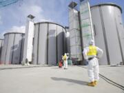 A worker in a protective suit and a mask looks at tanks, under construction, to store radioactive water, in the J1 area at Tokyo Electric Power Co's tsunami-crippled Fukushima Daiichi nuclear power plant in northeastern Japan.