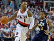 Portland Trail Blazers guard Damian Lillard , left, dribbles past Utah Jazz guard Trey Burke during the first half of an NBA preseason basketball game in Portland, Ore., Sunday, Oct. 18, 2015.