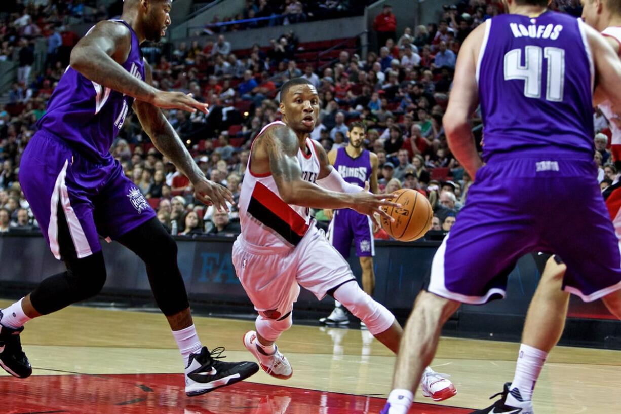 Portland Trail Blazers guard Damian Lillard, center, drives past Sacramento Kings center DeMarcus Cousins during the second half of an NBA preseason basketball game in Portland, Ore., Monday, Oct. 5, 2015.