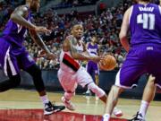 Portland Trail Blazers guard Damian Lillard, center, drives past Sacramento Kings center DeMarcus Cousins during the second half of an NBA preseason basketball game in Portland, Ore., Monday, Oct. 5, 2015.