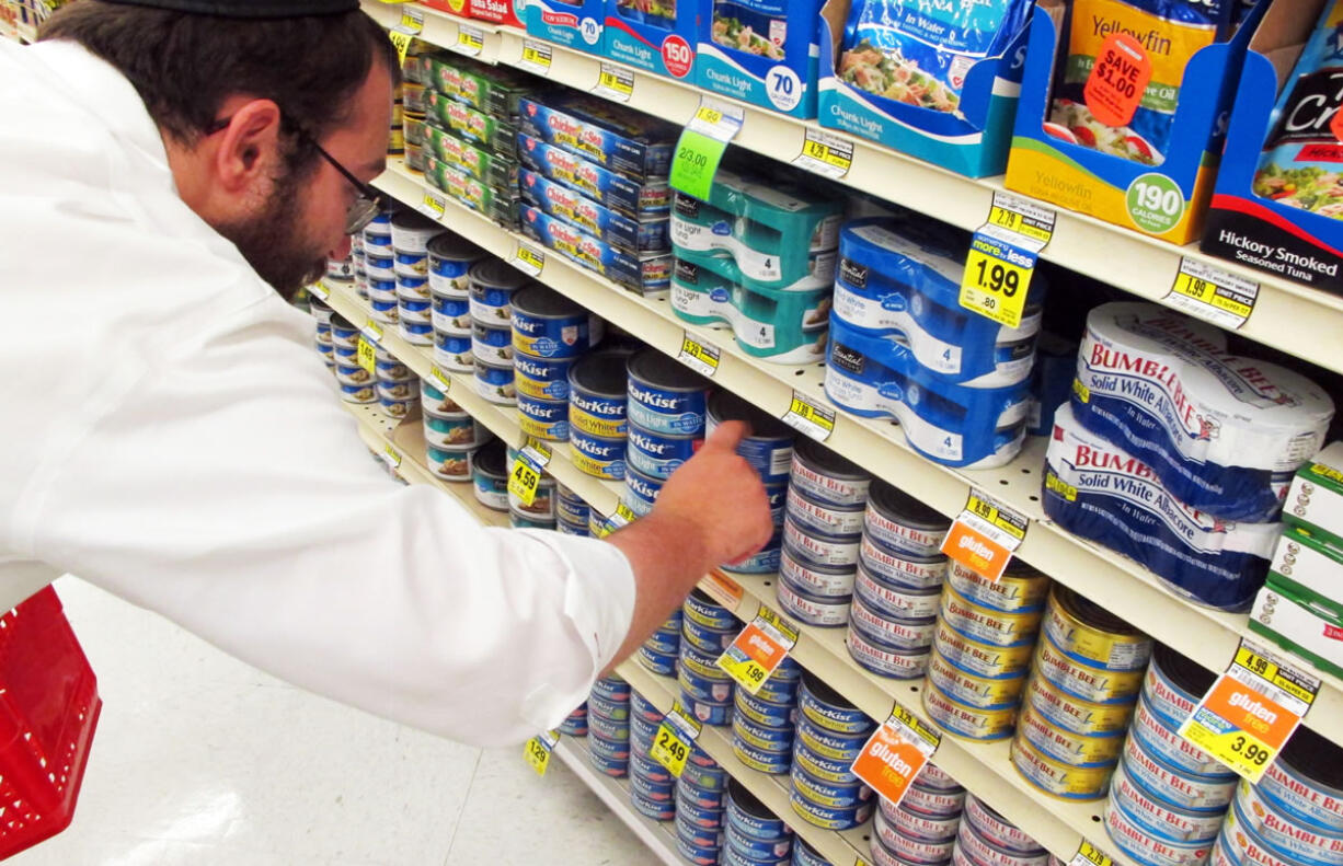 Orthodox Jewish rabbi Dovid Lepkivker looks through cans of tuna in a grocery store in Helena, Mont. Lepkivker and fellow rabbi Eli Chaikin are on a mission to reach as many Montana Jews as they can to teach them how to keep kosher.