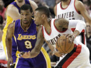 Portland Trail Blazers guard Damian Lillard, right, drives on Los Angeles Lakers guard Ronnie Price during the first half in Portland, Ore., Monday, Jan. 5, 2015. Lillard finished with 39 points in the Blazers' 98-94 win.