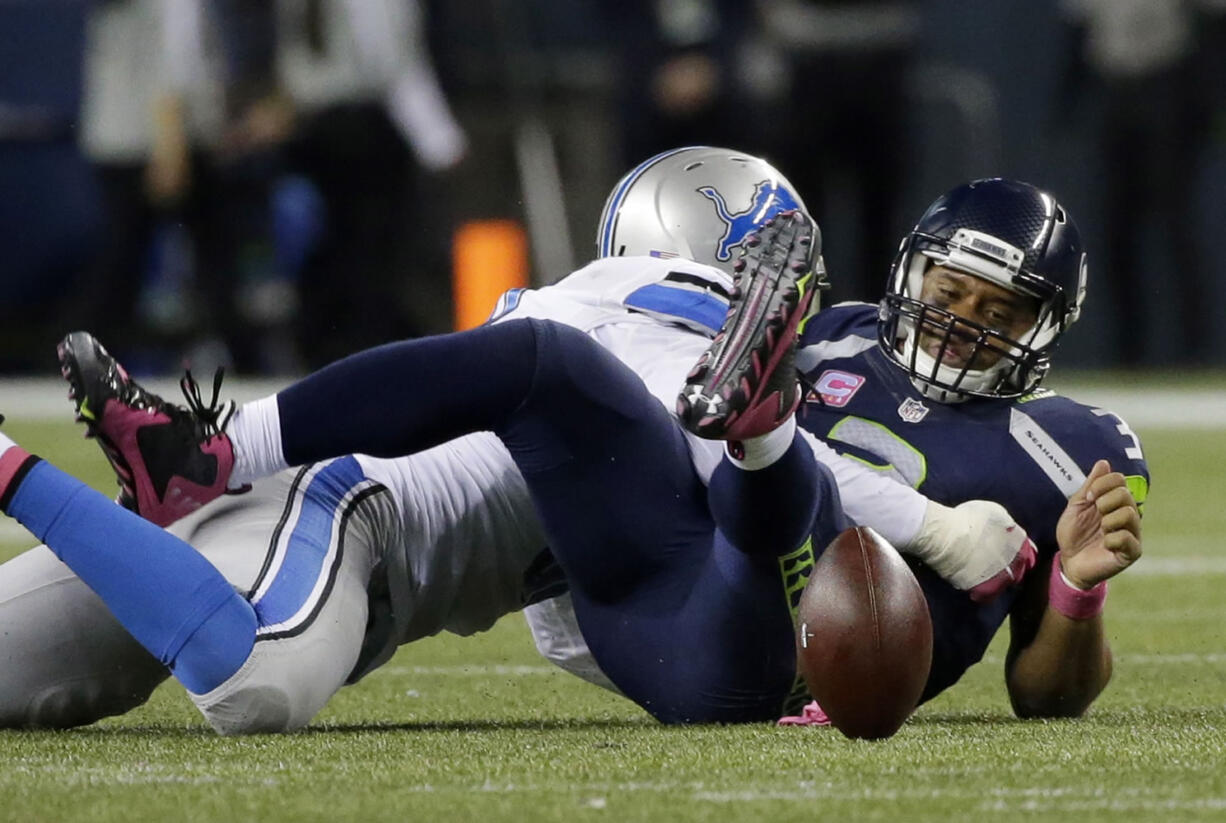 Seattle Seahawks quarterback Russell Wilson, right, spent several plays during Monday&#039;s game on his back or running to elude Detroit Lions defenders.