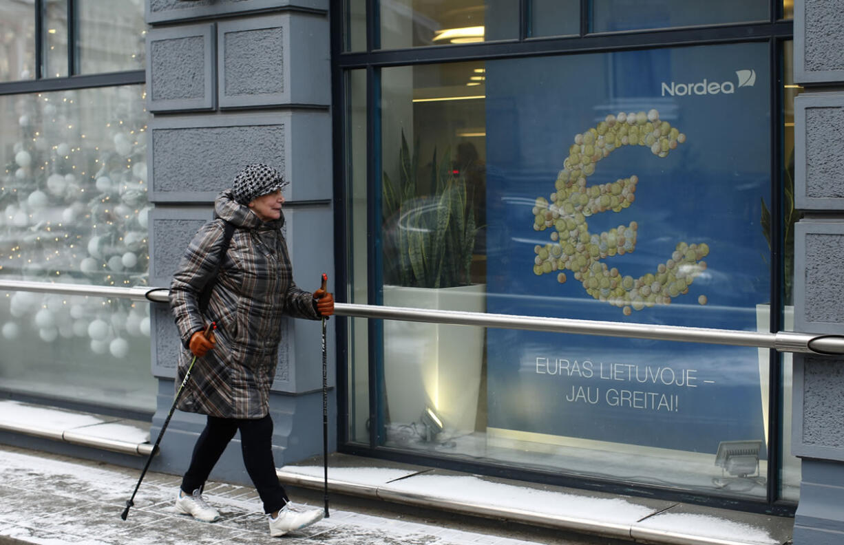 A woman passes a poster reading, &quot;The euro is coming to Lithuania soon,&quot; on Monday in Vilnius, Lithuania.