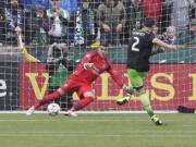 Seattle Sounders midfielder Clint Dempsey, right, scores on a penalty kick to tie the game against Portland Timbers goalkeeper Andrew Weber late in the second half of an MLS soccer game in Portland, Ore., Saturday, April 5, 2014. The two teams tied 4-4.