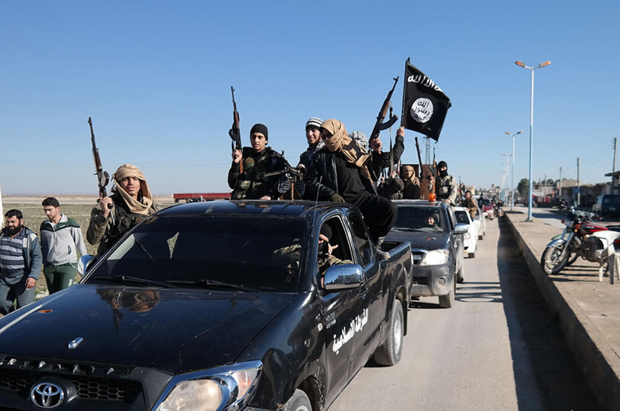 Islamic State militants pass by a convoy May 4 in Tel Abyad, northeast Syria. The Islamic State rakes in up to $50 million a month from selling crude from oilfields under its control in Iraq and Syria, part of a well-run oil industry that U.S. diplomacy and airstrikes have so far failed to shut down, according to Iraqi intelligence and U.S.