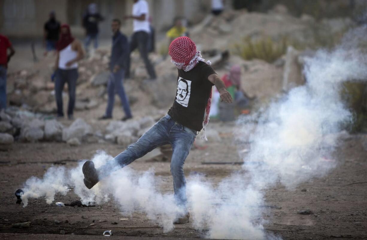 Palestinian kicks a tear gas canister that was fired by Israeli troops during clashes near Ramallah, West Bank, on Thursday.