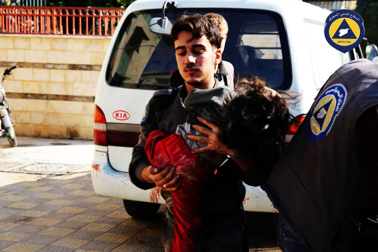 A paramedic holds a child from a market Friday after witnesses said it was hit by Syrian government forces in Douma, Syria. The Syrian Observatory for Human Rights and the Local Coordination Committees group said government forces fired more than 11 missiles at a market in Douma, killing at least 40. The United States announced Friday it is sending special operations forces to northern Syria.