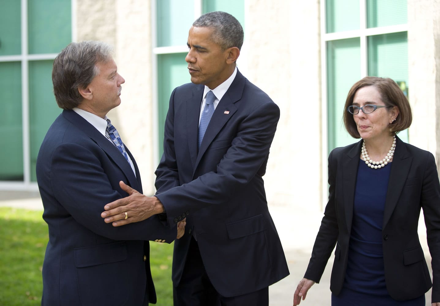 President Barack Obama, center, shakes hands with Roseburg Mayor Larry Rich, left, as Oregon Gov. Kate Brown looks on following their meeting Friday in Roseburg, Ore., with families of the victims of the Umpqua Community College shooting.