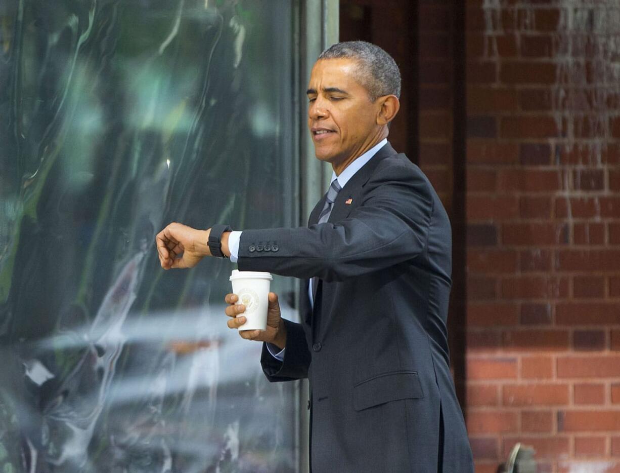 President Barack Obama checks his watch while walking back to the White House in Washington, Monday, Oct. 26, 2015, after a short trip to the nearby Metropolitan Club to attend a luncheon hosted by former Senators Tom Daschle and George Mitchell.