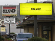 Signs calling for prayers and remembrance for those killed in a fatal shooting at Umpqua Community College, are seen on a pair of local businesses Saturday in Roseburg, Ore.