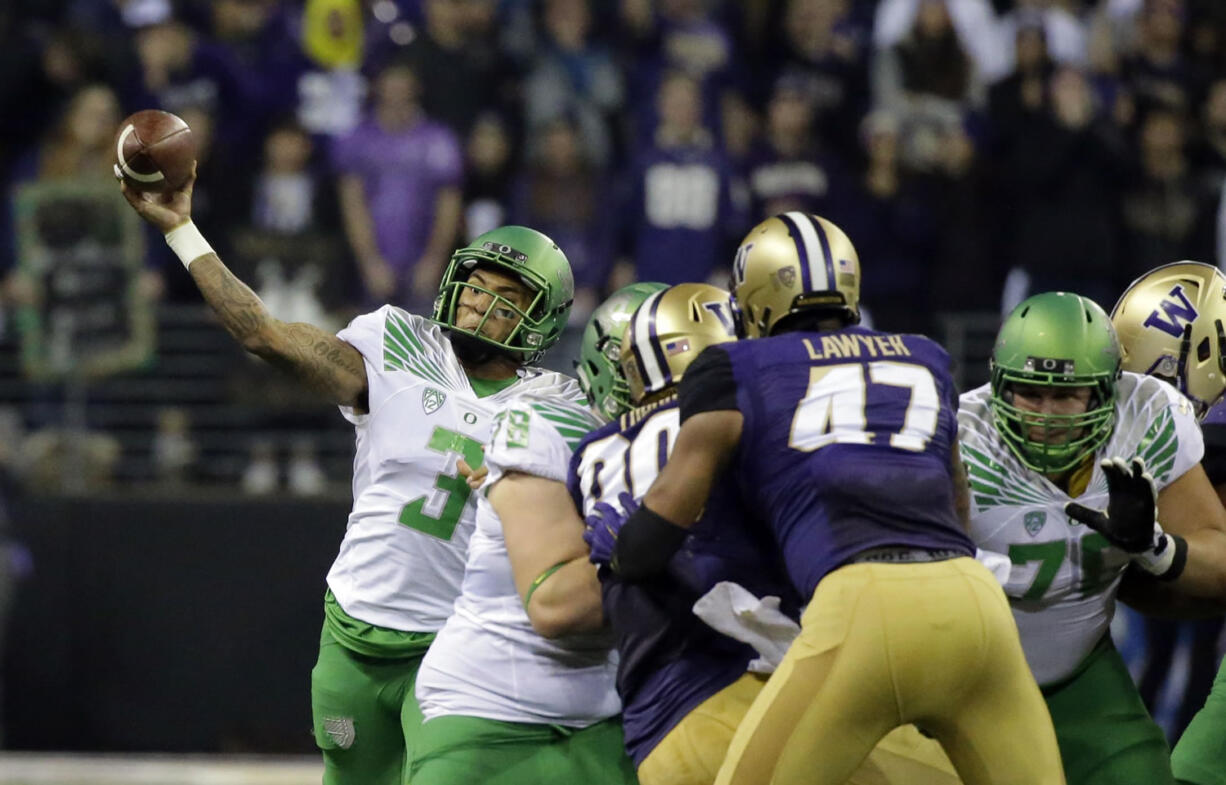 Oregon quarterback Vernon Adams Jr., left, passes around his blockers in the first half of an NCAA college football game against Washington, Saturday, Oct. 17, 2015, in Seattle. (AP Photo/Ted S.