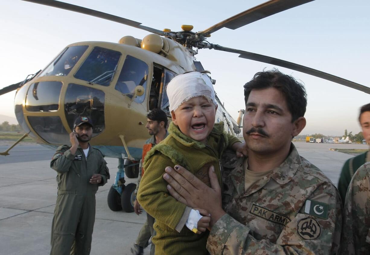A Pakistani soldier carries an injured child who was airlifted from Chitral following Monday&#039;s deadly earthquake, at Peshawar airbase in Pakistan on Tuesday. Rescuers are struggling to reach quake-stricken regions in Pakistan and Afghanistan on Tuesday as officials said the combined death toll from the previous day&#039;s earthquake rose to hundreds.