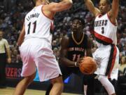 New Orleans Pelicans guard Jrue Holiday, center, finds himself trapped by Portland Trail Blazers center Meyers Leonard, left, and guard C.J. McCollum (3) during the first quarter of an NBA basketball game in Portland, Ore., Wednesday, Oct. 28, 2015.