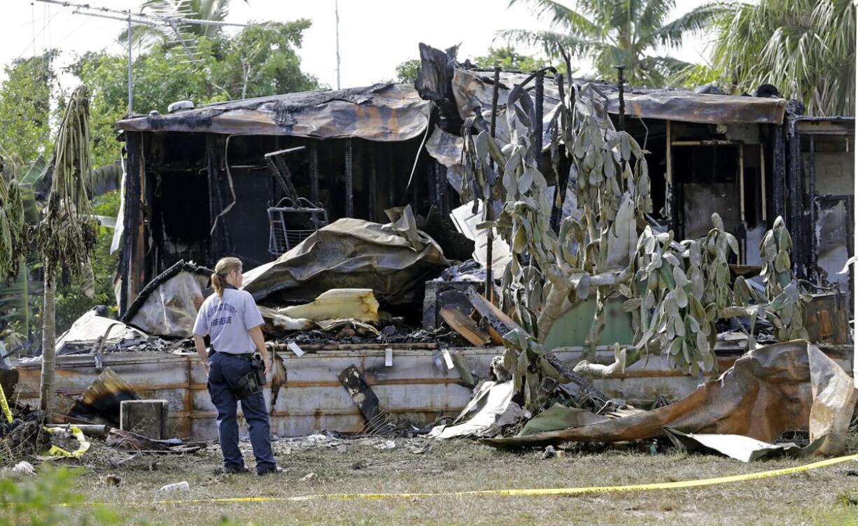 A Palm Beach County Fire Rescue worker looks at a mobile home where a small plane crashed Wednesday in Palm Springs, Fla.