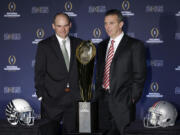 Ohio State head coach Urban Meyer, right, and Oregon head coach Mark Helfrich pose with the championship trophy after a news conference before the NCAA college football playoff championship game Sunday, Jan. 11, 2015, in Dallas. Oregon plays Ohio State in the championship game on Monday. (AP Photo/David J.