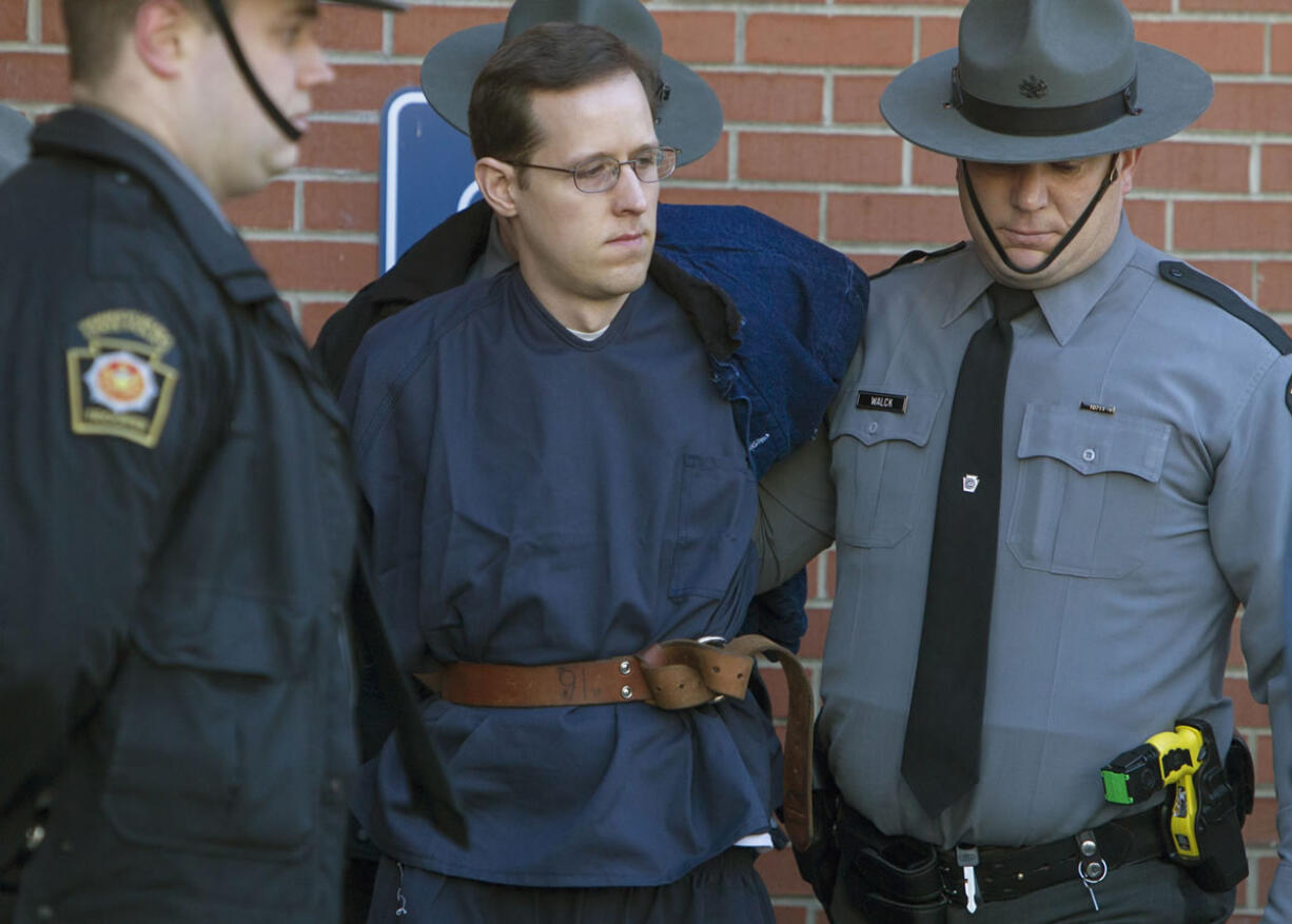 Eric Frein, center, is escorted out of the Pike County Courthouse after his preliminary hearing in Milford, Pa., Monday, Jan. 5, 2015. Frein is charged with fatally shooting a Pennsylvania state trooper and wounded another during an ambush at their barracks in September. A judge on Monday ordered Frein to stand trial on the charges. Prosecutors are seeking the death penalty. Frein led authorities on a 48-day manhunt through the Pocono woods before marshals captured him at an abandoned airplane hangar.