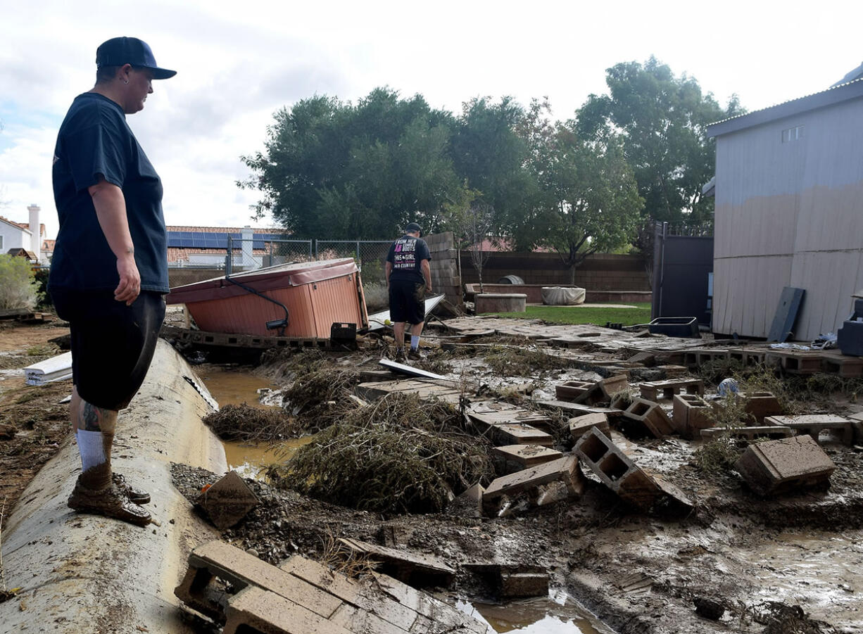 Rochelle Price, left, and Jen Dunnagan, survey damage Friday after being rescued by firefighters when floodwater surrounded their home on Thursday in Lancaster, Calif.