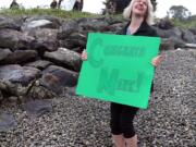 Elinor Fanning holds a sign for her husband, Mark Powell, of Bainbridge Island as he finishes the last leg of his Swim Duwamish project Wednesday in Seattle.